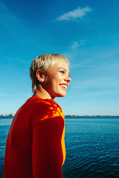 Woman looks toward the sea in a sunlit summer portrait outdoors
