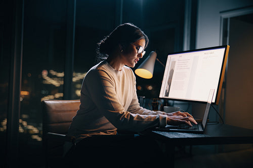 Creative businesswoman typing on her laptop during a night shift