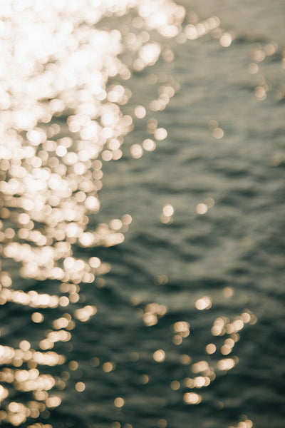 Golden sunlight reflecting on serene water creating mesmerizing bokeh effect at dawn