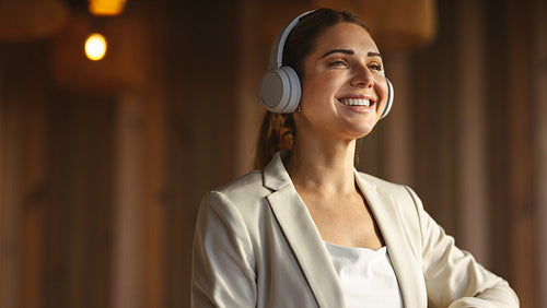 Smiling businesswoman in cafe with earphones listening to music