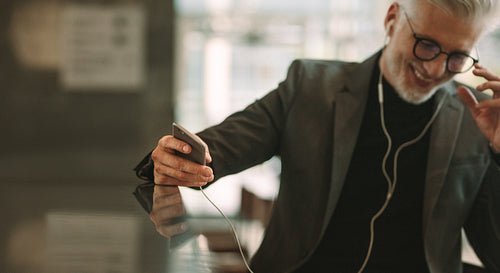 Mature businessman sitting at cafe with phone