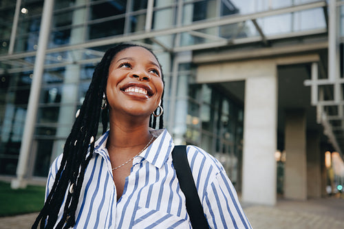 Cheerful young businesswoman smiling and looking away while commuting in the city