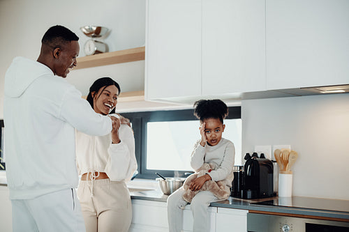 Adorable girl getting shy as her parents hold each other romantically