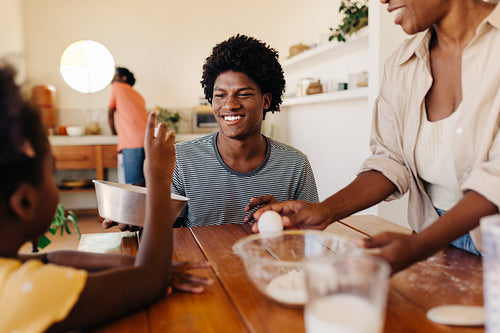 Black Brazilian family baking a cake together at their kitchen table