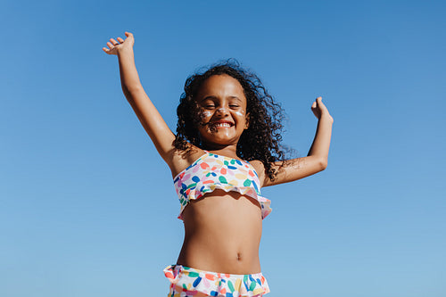 Happy girl enjoying summer vacation on the beach with blue skies