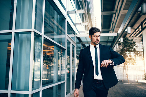 Young businessman looking at his watch while walking at airport