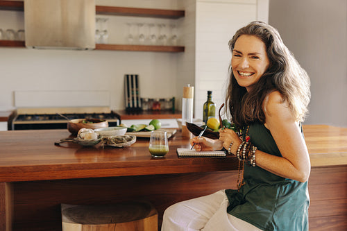 Vegetarian woman writing down her meal plans and recipes in her kitchen