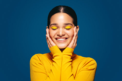Empowered by makeup, confident young woman smiles as she embraces her face