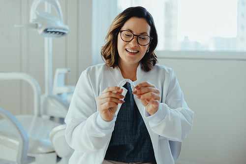 Female dentist holding clear aligner in dental clinic portrait