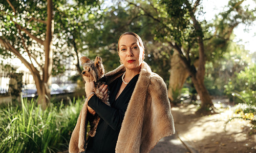 Posh woman holding her puupy outdoors