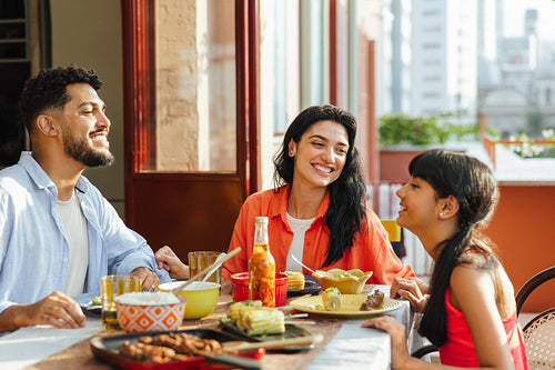 Smiling latin family enjoying a meal together in a sunny outdoor setting