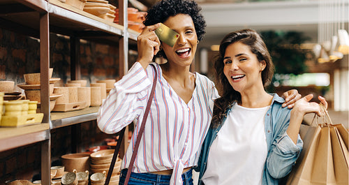 Happy young women shopping with a credit card in a ceramic store