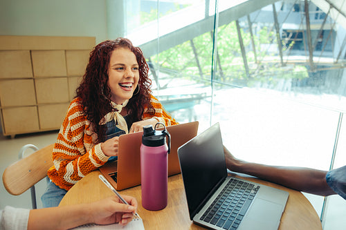 Female university student engaging in a collaborative study session at a modern city campus, sharing ideas and fostering a lively academic atmosphere