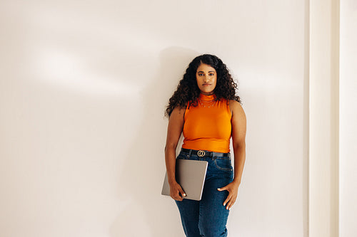 Confident young businesswoman standing a wall in an office