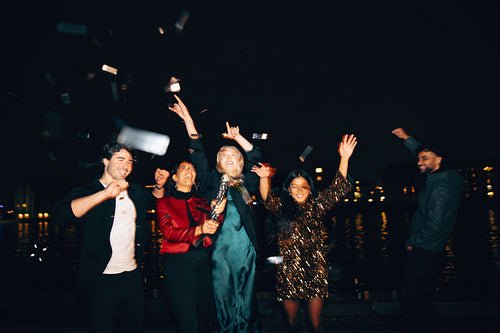 Group of friends celebrating with confetti outdoors at nighttime