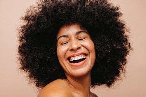 Woman with Afro hair laughing happily in a studio