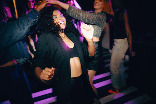 Friends dancing together under vibrant lights at a lively nightclub
