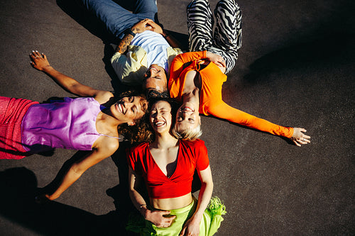 Circle of friends lies together on the ground outdoors in the city