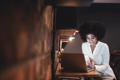 African woman looking at smartphone while working in office