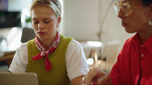 Coworker joins women as they review a laptop in a cafe workspace