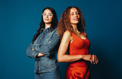 Women stand together in a studio portrait with confidence against a blue background