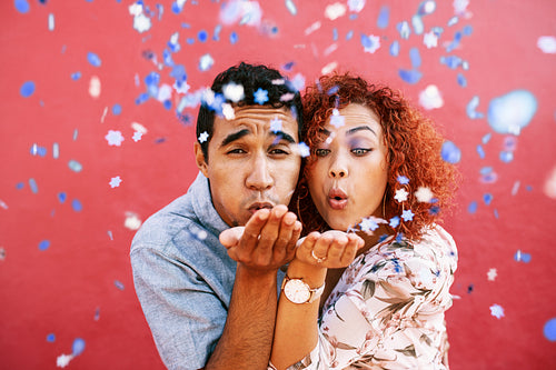 Happy young couple blowing confetti in celebration of their love.