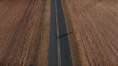 Cyclist riding bike on long countryside road