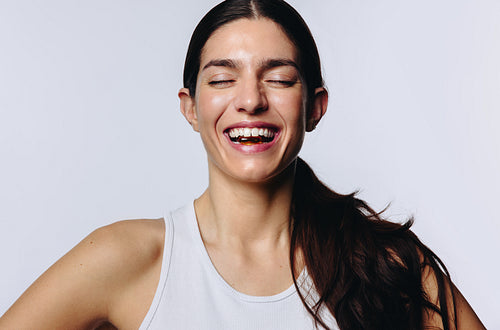 Woman in studio laughing while taking a vitamin capsule