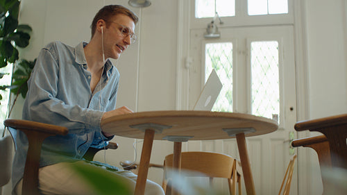 Talking man joins a laptop video call at a modern workspace table