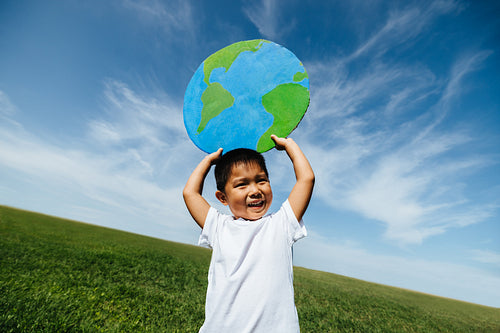 Boy learning about the world with paper globe outdoors