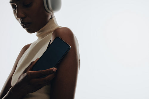 Woman with smartphone and headphones against a light background