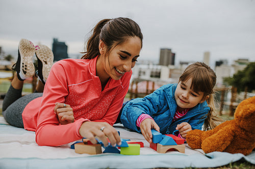 Girl playing building blocks with her nanny at the park
