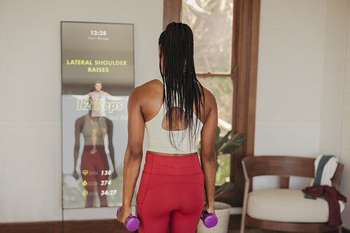 Smart fitness mirror: Woman doing weight training with virtual instructor