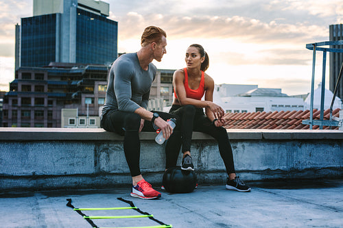 Fitness couple sitting on rooftop during workout