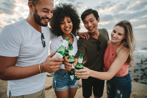 Group of friends having fun at the beach toasting beer