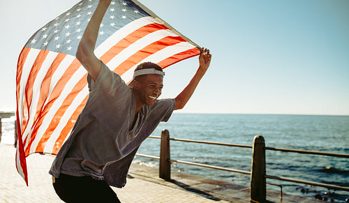 Cheerful young guy at promenade with american flag