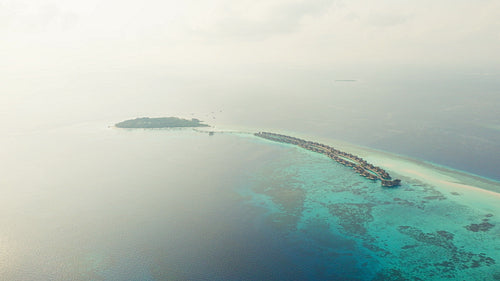 Aerial view of a luxury island resort with overwater bungalows in a tropical paradise ocean