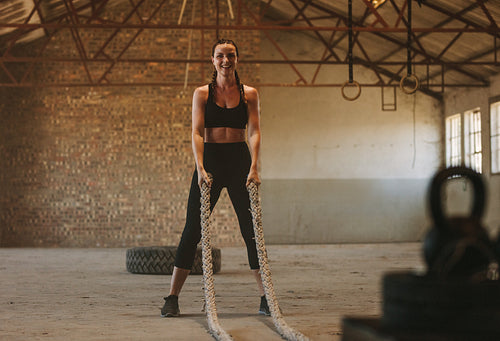 Woman with battling rope in old warehouse