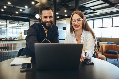 Colleagues smiling while looking at a laptop