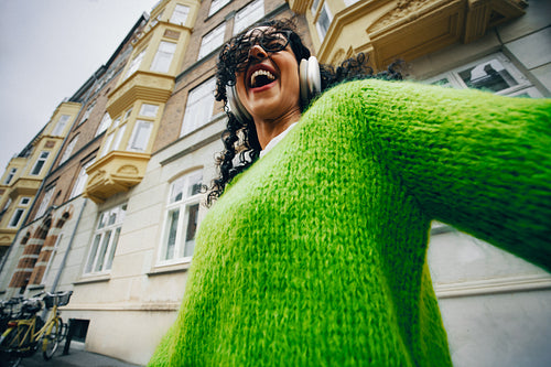 The woman enjoys carefree music with headphones on her city walk