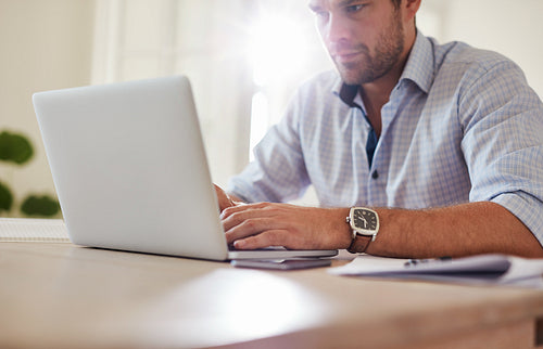 Young man sitting at table and using laptop