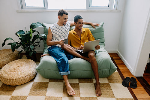 Happy couple relaxing together on sofa with a laptop in their home