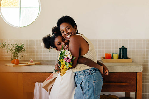 Mother and daughter embrace in floral surprise at home
