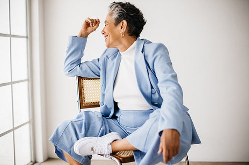 Senior business woman sitting on a chair in her office, dressed in a suit
