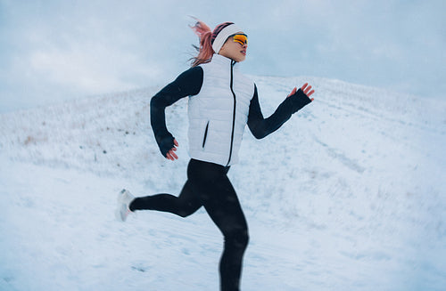 Trail running takes the woman across a mountain path in winter snow