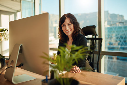 Smiling female entrepreneur sitting at her desk