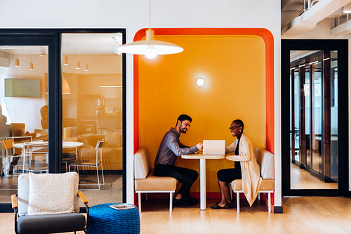 Two professionals discussing work in cozy office seating area