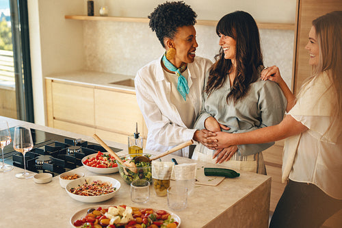 Pregnant woman cooking with friends during a relaxed home gathering