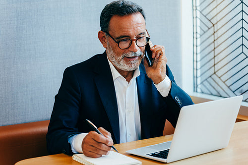 Senior executive working on laptop and making a phone call