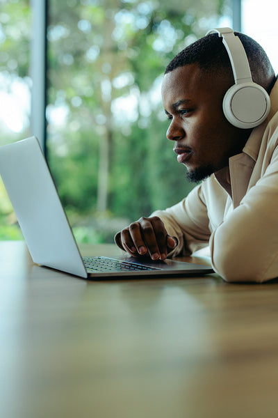 Focused young man using laptop while listening to music